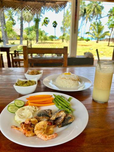 a table with two plates of food and a drink at 108 Palms Beach Resort in Trincomalee