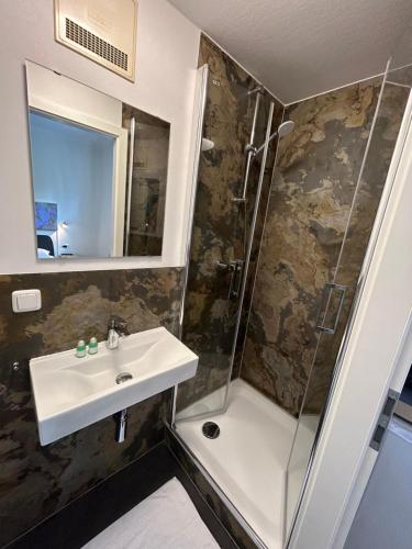 W łazience znajduje się umywalka i prysznic. w obiekcie Riverside Airport Hotel w mieście Kelsterbach