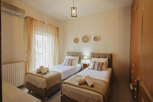 a bedroom with two beds and a window at CITY CENTER VILLA HERSONISOS in Hersonissos