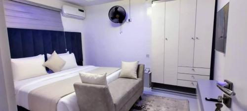 a bedroom with a large white bed and a chair at Beautiful One Bedroom Apartment in Opebi, Ikeja in Ikeja