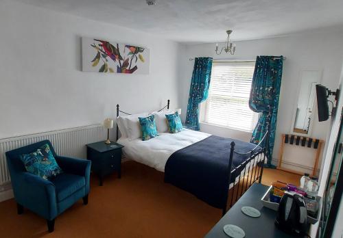1 dormitorio con 1 cama y 1 silla azul en Regency Guest House, en Neatishead