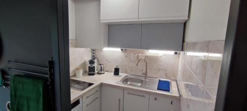 a kitchen with white cabinets and a sink at MICHELET Studio climatisé avec balcon et parking ferme in Montpellier