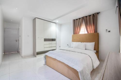 a white bedroom with a large bed and a window at Gorgeous Short-let Apartment Lekki in Lekki