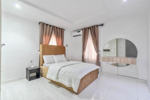a white bedroom with a bed and a mirror at Gorgeous Short-let Apartment Lekki in Lekki