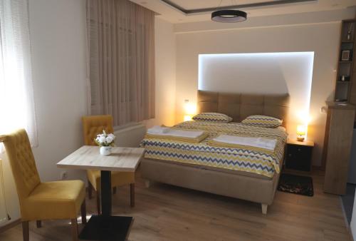a bedroom with a bed and a table and a chair at Danica apartman in Gornji Milanovac