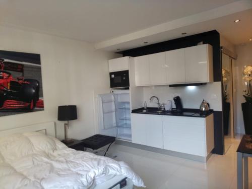 Cet appartement comprend une chambre avec un lit et une cuisine avec des placards blancs. dans l'établissement Eider croisette, à Cannes