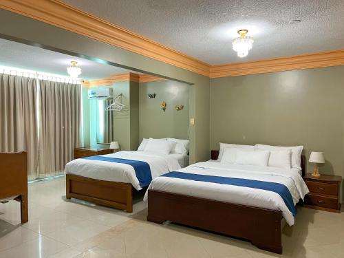 1 Schlafzimmer mit 2 Betten und einem großen Fenster in der Unterkunft Apart Hotel Hamilton in Manta