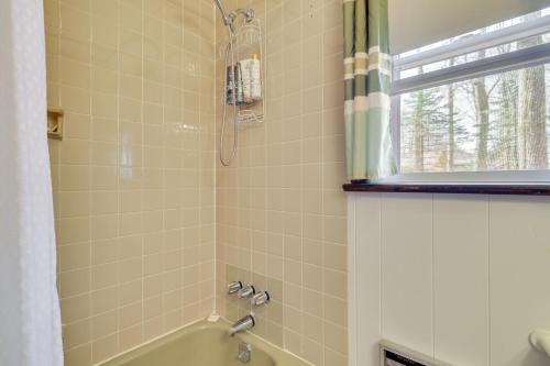 Un baño con bañera y ducha con ventana. en Cozy Pocono Lake Cottage with Fire Pit and Ping Pong!, en Pocono Lake
