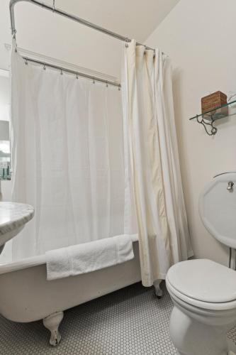 a bathroom with a white shower curtain and a toilet at Golden Gate Hotel in San Francisco