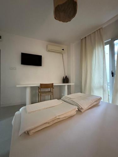 a white bedroom with two beds and a table at Villa Vele in Herceg-Novi