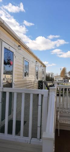 uma casa com um corrimão branco num convés em N and B caravan hire Flamingo Land em Kirby Misperton