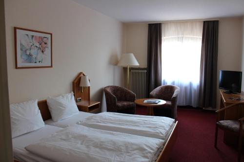 a hotel room with a bed and chairs and a window at Hotel zur Moselbrücke in Schweich