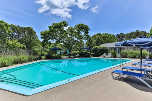 a swimming pool with chairs and umbrellas at Handkerchief Shoals Inn in Harwich