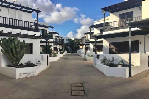 a row of white apartment buildings with potted plants at Duplex 3 dormitorios con parking privado in Costa Teguise