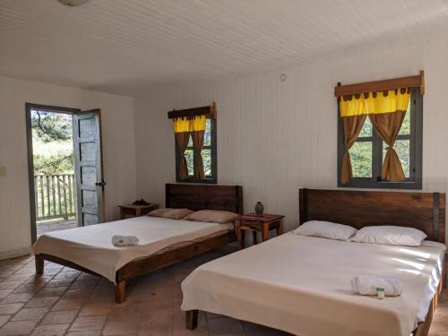 two beds in a room with two windows at Posada San Lázaro in Choluteca