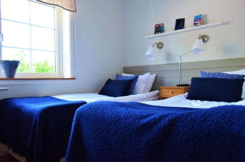 a bedroom with two beds with blue sheets and a window at Närebo Gårdshotell & Restaurang in Lidköping