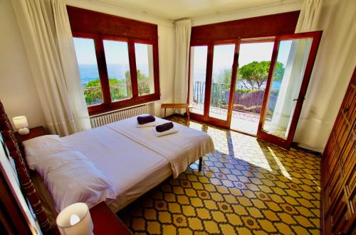 a bedroom with a bed in a room with windows at V&V LLORET- VILLA MEDITERRANIA preciosa villa con vistas panorámicas al mar y a solo 120m de la playa Cala Canyelles!! in Lloret de Mar