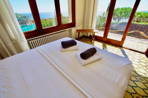 a bedroom with a white bed with two pillows on it at V&V LLORET- VILLA MEDITERRANIA preciosa villa con vistas panorámicas al mar y a solo 120m de la playa Cala Canyelles!! in Lloret de Mar