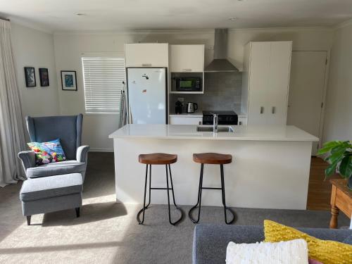a kitchen with a counter and two bar stools at Guesthouse in Papamoa Beach in Papamoa