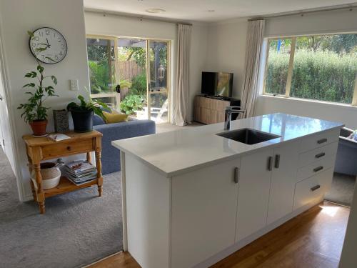 a white kitchen with a sink and a living room at Guesthouse in Papamoa Beach in Papamoa