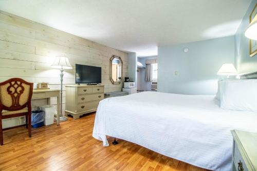 a bedroom with a white bed and a desk and a television at Sea View Motel in Ogunquit