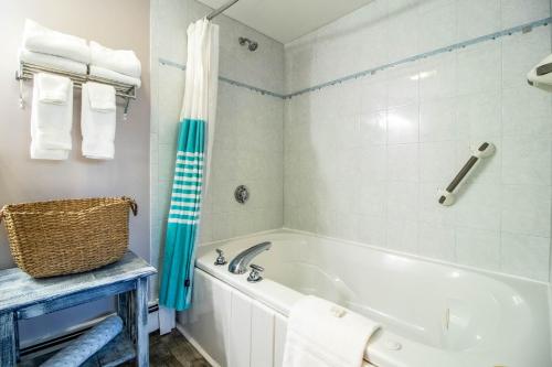 a bathroom with a white tub and a blue shower curtain at Sea View Motel in Ogunquit