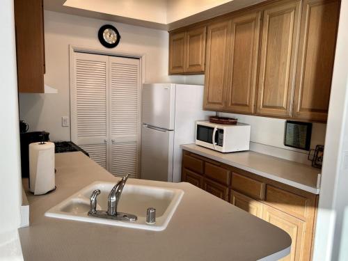 a kitchen with a sink and a white refrigerator at Oceanfront 2BR Condo, Private Beach & Patio, Rare Find in Carlsbad
