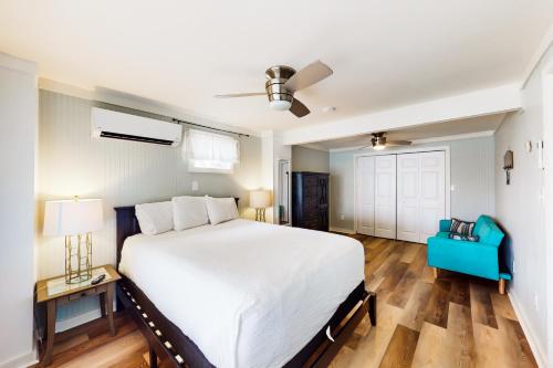 a bedroom with a large white bed and a blue chair at New Kids On The Dock in Destin