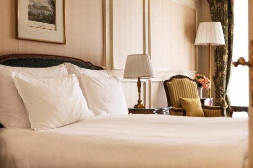 a bedroom with a white bed and a chair at Grand Hotel Wien in Vienna