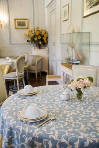une table avec des assiettes et un vase de fleurs dans l'établissement Malouinière Le Valmarin, à Saint-Malo