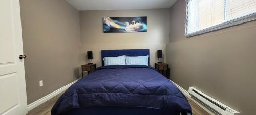 a bedroom with a bed with a purple comforter at Blue Wave 2 bedroom suite in Saskatoon