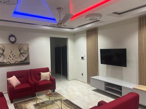 a living room with red chairs and a flat screen tv at Boulevard Court in Ejisu