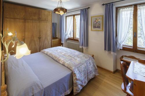 a bedroom with a bed and a table and windows at Villa Casanova - Stayincortina in Cortina dʼAmpezzo