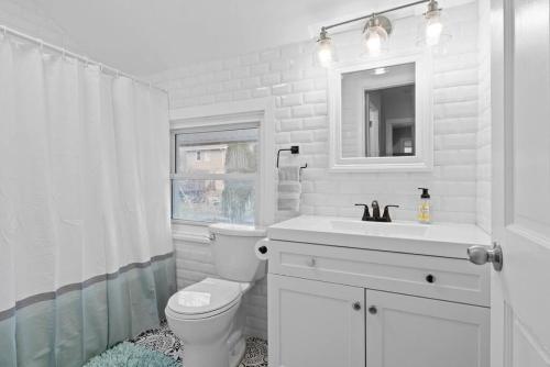 a white bathroom with a toilet and a sink at Charming 3-Bedroom Home Near Downtown Free Parking in Pittsburgh