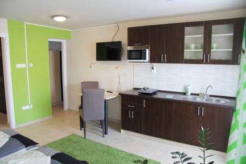 a kitchen with a sink and a desk in a room at Írisz Apartmanház in Mórahalom
