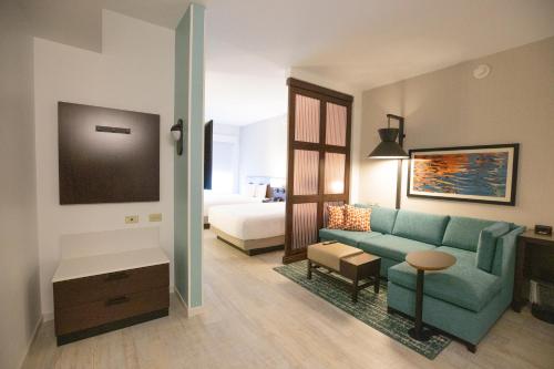 a living room with a blue couch and a bed at Hyatt Place West Palm Beach in West Palm Beach