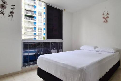 een slaapkamer met een wit bed en een groot raam bij 208 APARTAMENTO VACACIONAL AKUA RESORT® in Ricaurte