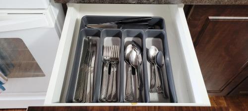 a drawer filled with silver utensils in a refrigerator at Blue Wave 2 bedroom suite in Saskatoon