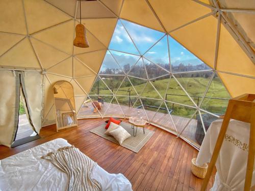 a room with a tent with a large glass window at Bohemia Glamping 