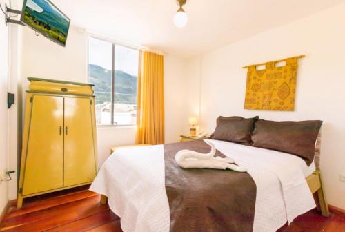 a bedroom with a bed and a yellow cabinet at HOSTAL DEL RÍO in Ibarra