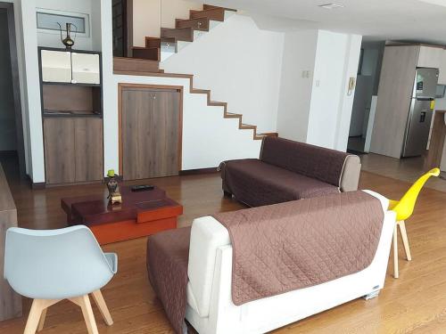 ein Wohnzimmer mit einem Sofa und einem Stuhl in der Unterkunft Departamento nuevo, elegante y muy cómodo. in Loja
