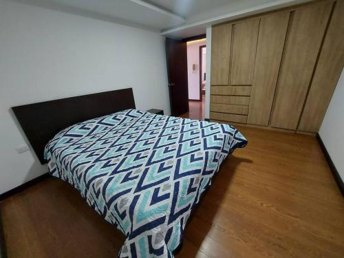 a bedroom with a bed and a wooden floor at Departamento amplio y cómodo en el centro de la ciudad in Loja