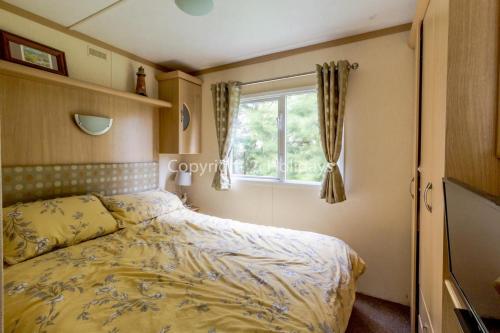 um quarto com uma cama e uma janela em 8 Berth Caravan At Orchards Haven In Clacton-on-sea, Essex Ref 15007o em Clacton-on-Sea