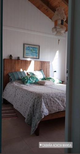 a bedroom with a large bed with a wooden headboard at Cabaña Acacia Mansa in Villa Giardino