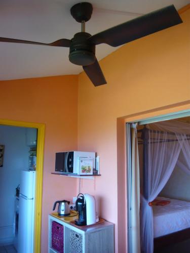 a room with a ceiling fan and a room with a bed at Bigouz résidence la plage de l'anse Caritan in Sainte-Anne