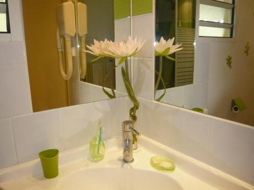 un lavabo con un jarrón de flores. en Bigouz résidence la plage de l'anse Caritan, en Sainte-Anne