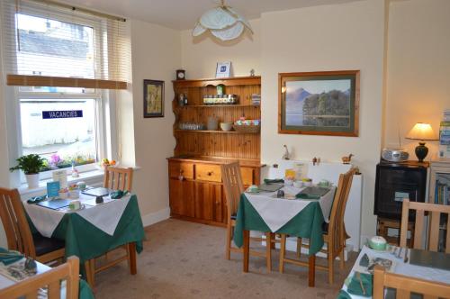 a dining room with two tables and a kitchen at Beckside Guest House Keswick in Keswick