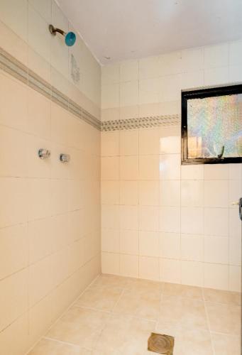 une salle de bain carrelée blanche avec une douche et une fenêtre dans l'établissement Casa Huitzilin, à Mexico