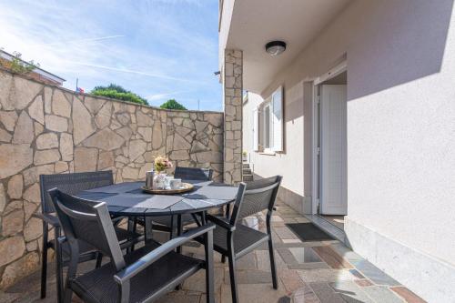 stół i krzesła na patio z kamienną ścianą w obiekcie Apartment Medulin 2274d w Medulinie