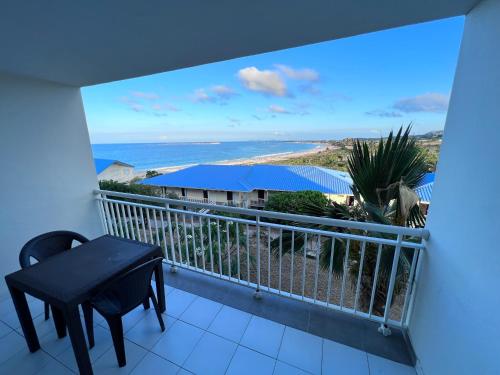 a balcony with a table and a view of the ocean at Studio Tortola Orient Bay VUE MER in Cul de Sac